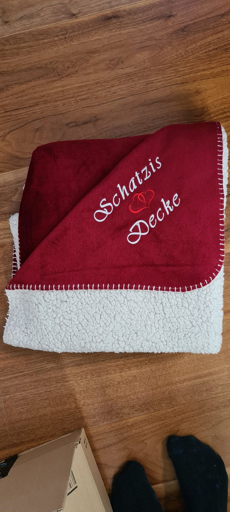 Weinrote Decke mit dem gestickten Schriftzug Schatzis Decke und einem Herz