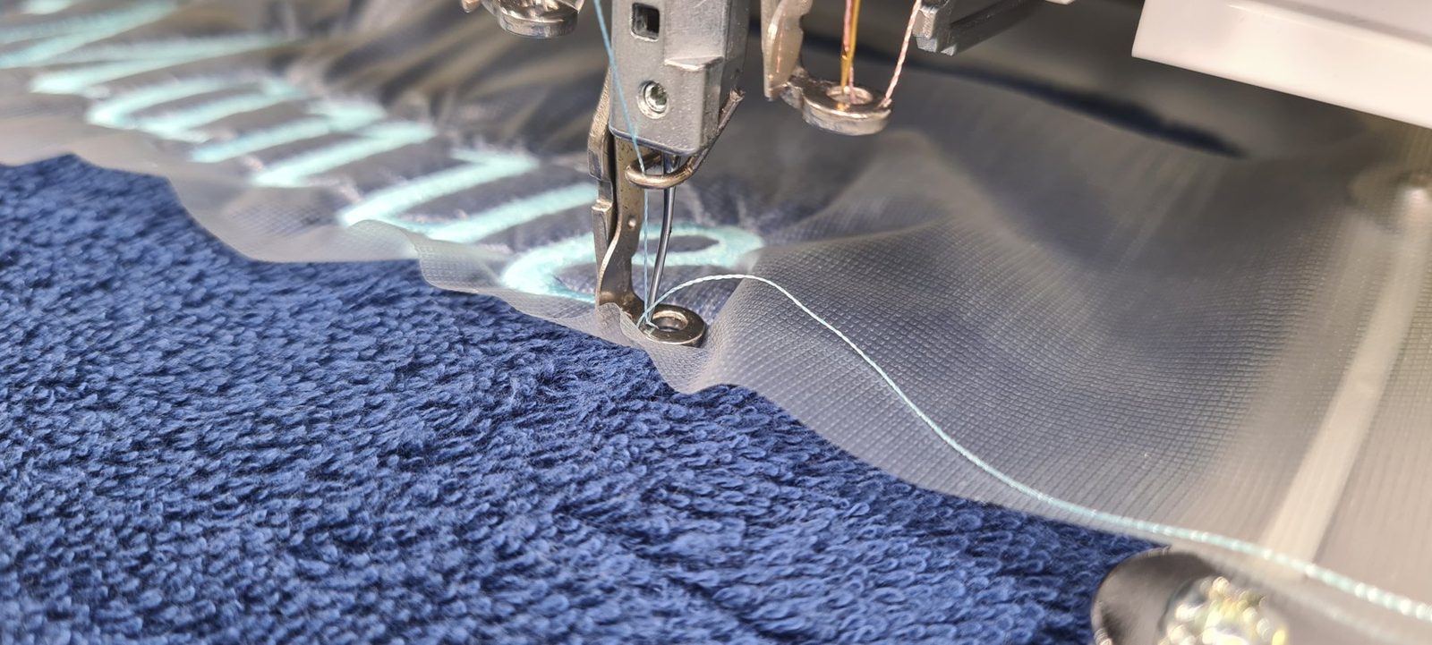 Ein blaues Handtuch wird in der Stickmaschine bestickt