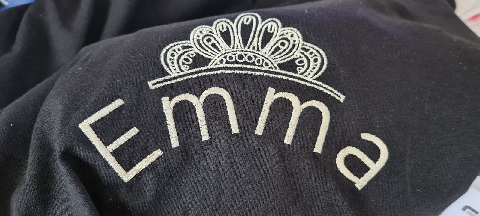 Dunkler Pulli mit dem gestickten Namen Emma unter einer Krone